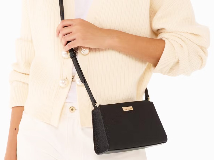woman in a cream sweater with a black glitter crossbody bag