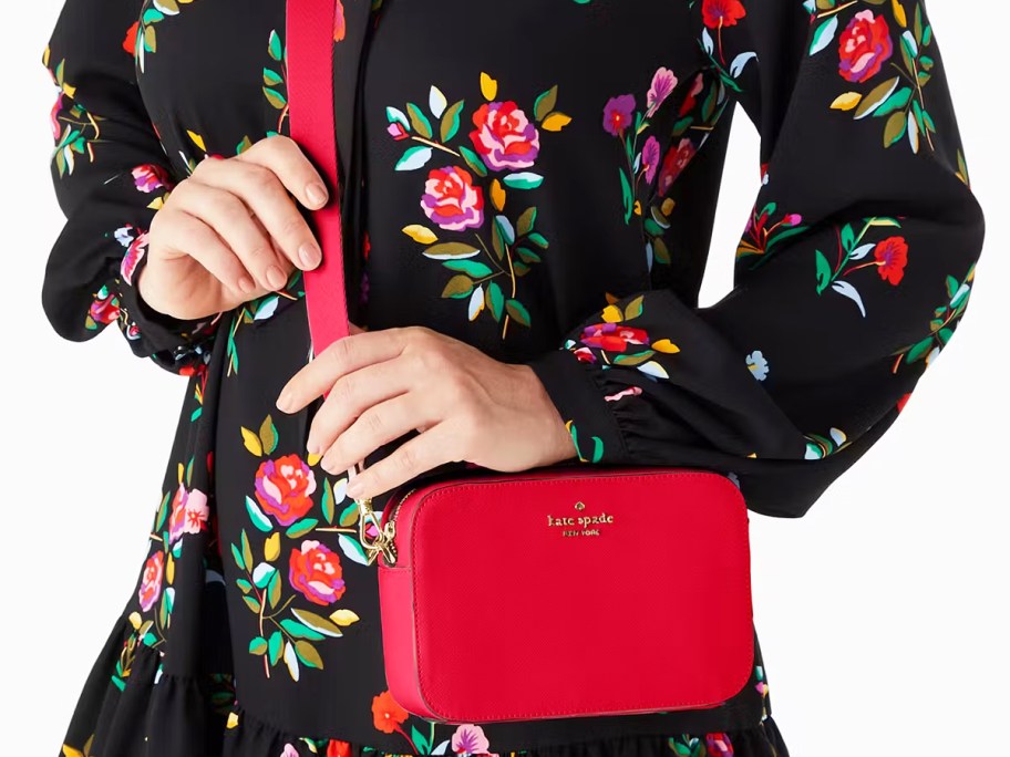 woman in a black floral print dress with a red crossbody bag