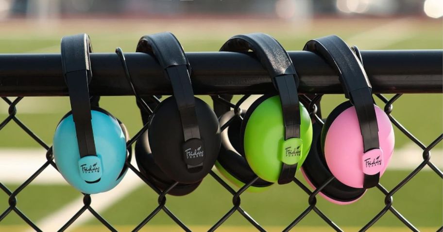 4 pairs of noise-cancelling baby headphones hanging on a fence