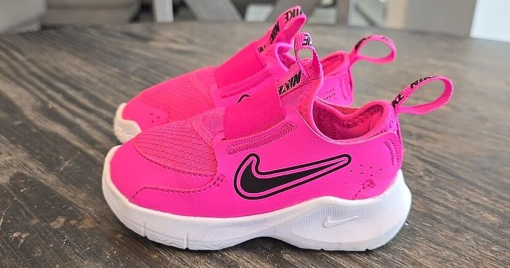 hot pink Nike Flex Runner 3 shoes on wooden table