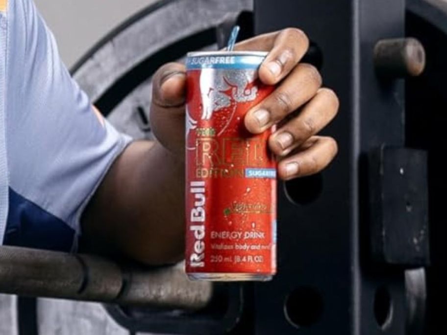 A person holding a can of Red Bull at the gym