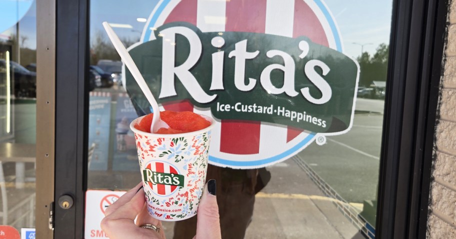 hand holding up an italian ice in a cup with a rita's sign in background