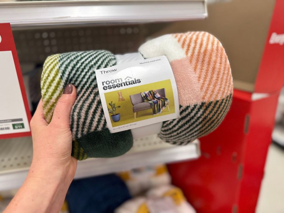 A person holding a multicolored blanket in a store