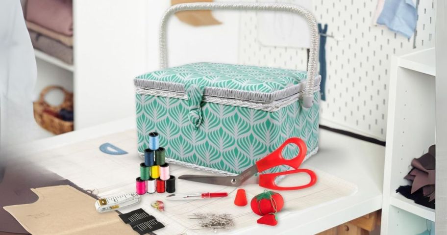 a green and white Singer Sewing Basket with various sewing supplies and scissors on a table