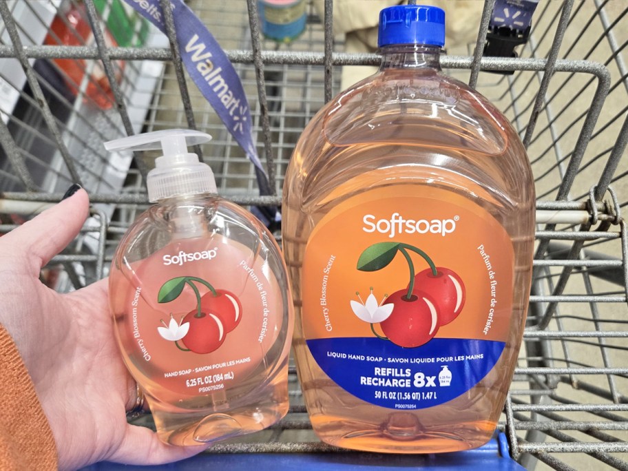 hand holding a bottle of Softsoap Cherry Blossom hand soap in cart next to large refill bottle