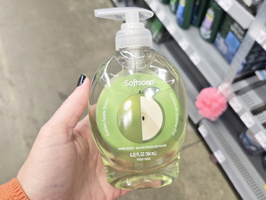 hand holding up a green bottle of Softsoap golden apple hand soap in store