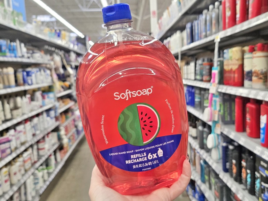 holding up a large pink refill bottle of softsoap watermelon hand soap in store