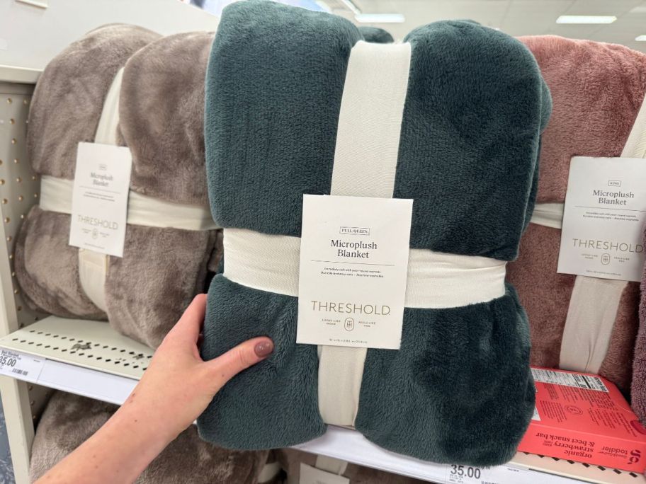 A person holding a green blanket in a store