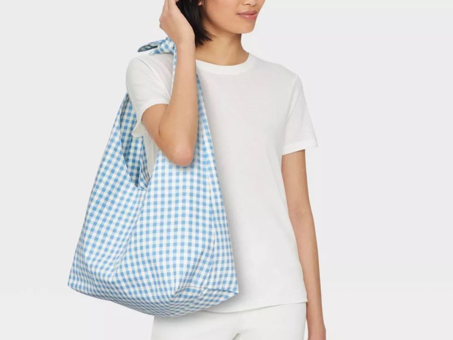 A woman carrying a blue and white Universal Thread Knotted Slouchy Shoulder Tote Bag