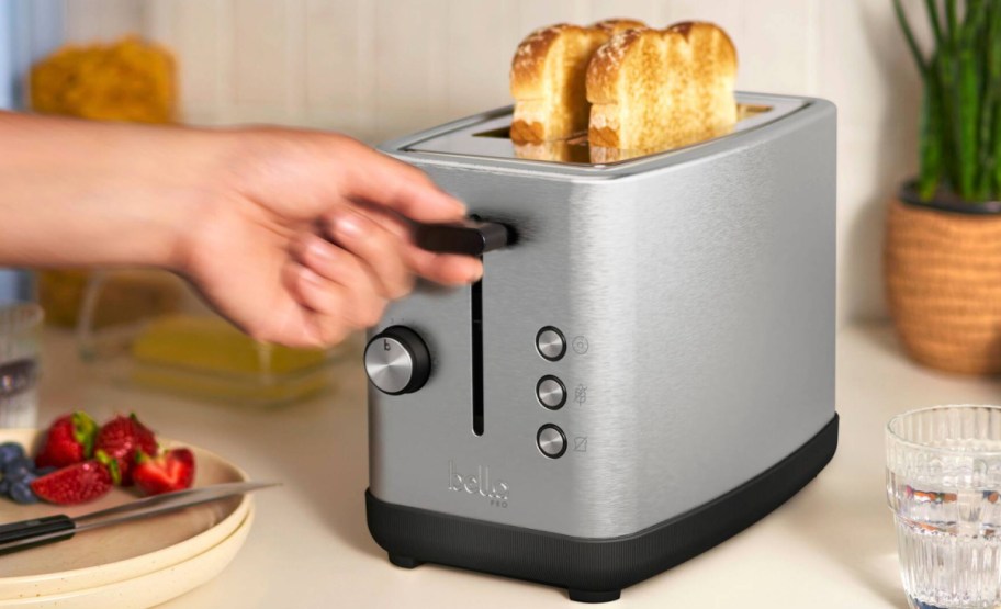 hand holding toaster handle to press the toast down