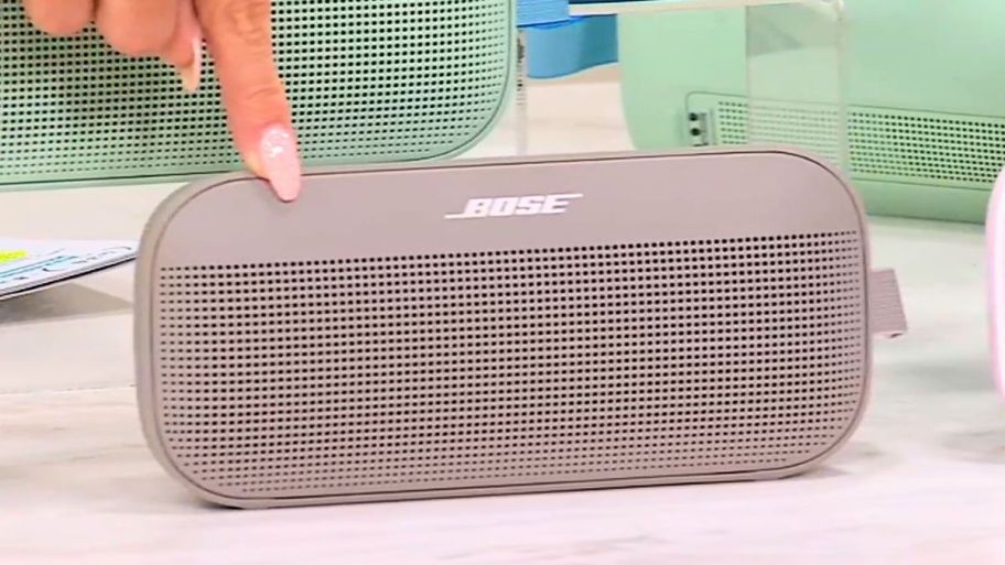 finger pointing to beige bose speaker