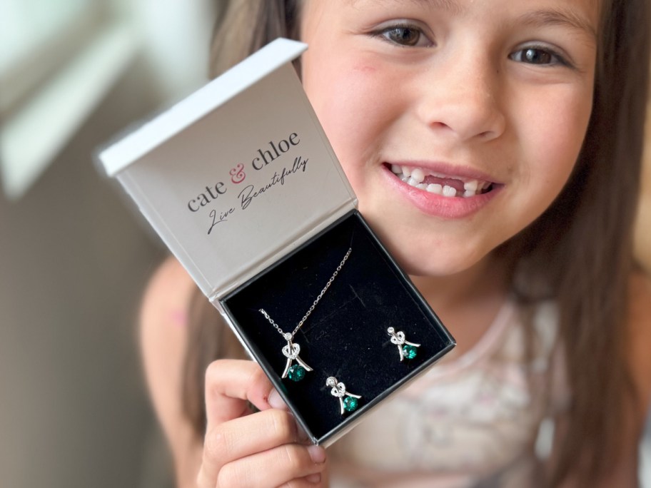 girl holding jewelry box with necklace and earrings near face