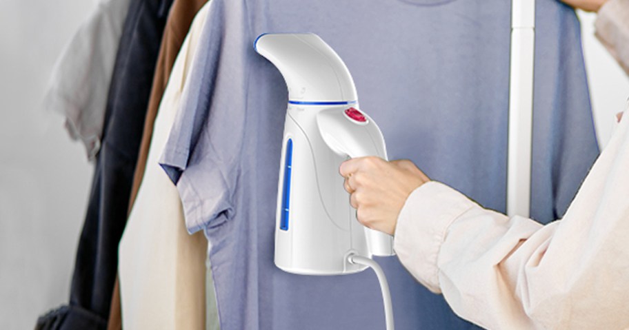 person using a clothes steamer to get wrinkles out of a blue shirt