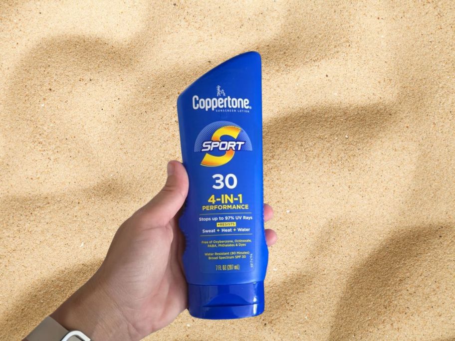 Coppertone Sport Sunscreen SPF 30 Lotion 7oz bottle in hand above sand