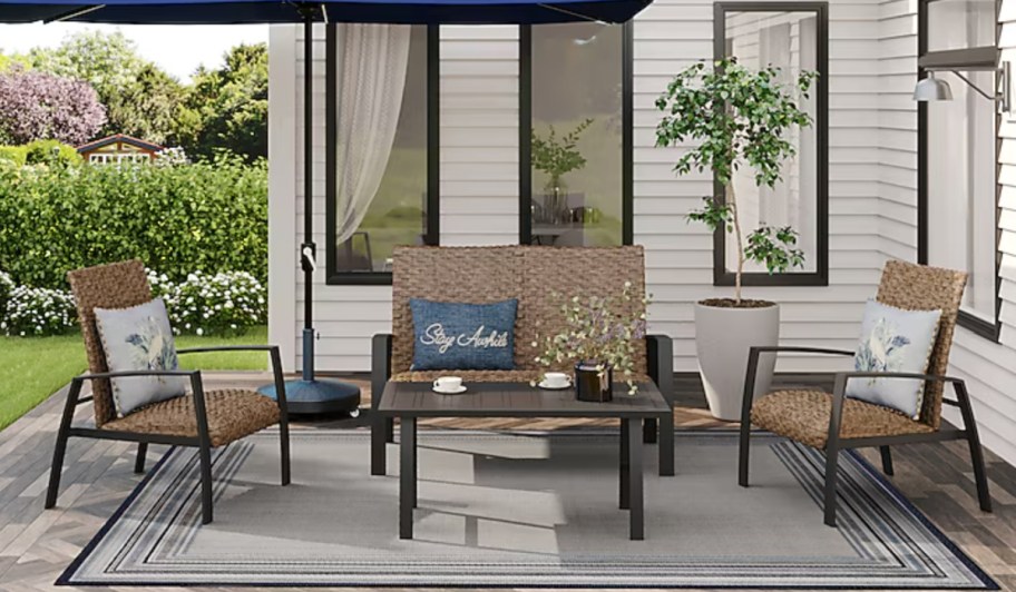 4 piece wicker patio set with black frame under blue umbrella