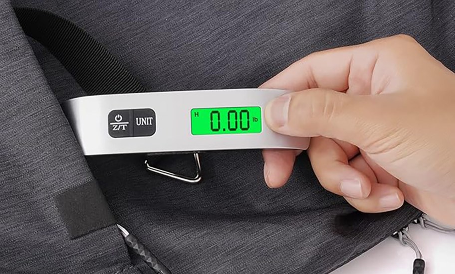person holding a digital luggage scale