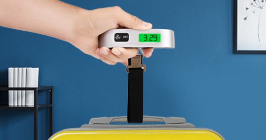 person using a digital luggage scale to weigh their luggage
