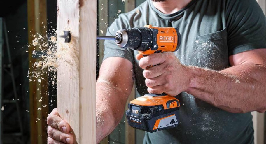 man using power tool on a wood wall