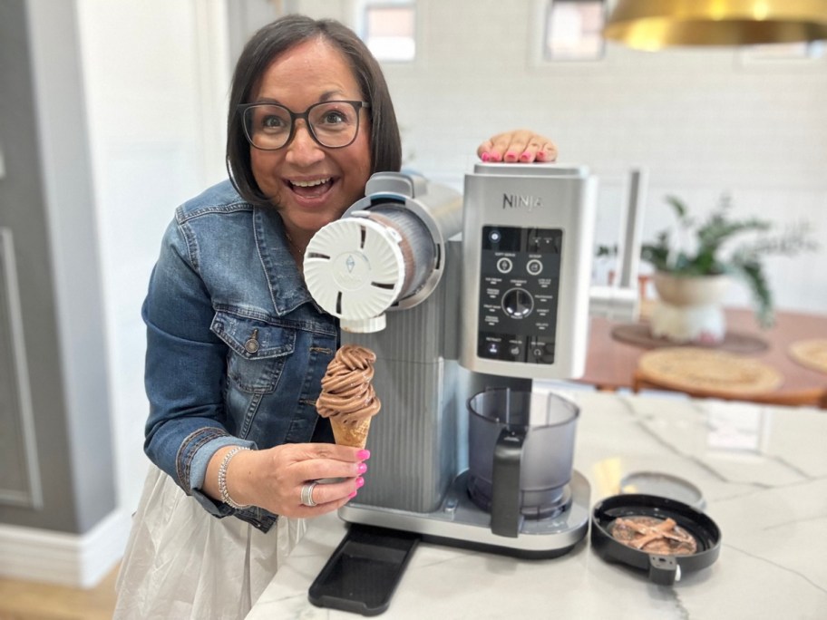 woman posing with an ice cream cone next to a ninja creami swirl machine