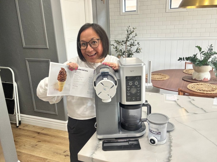 woman holding up a recipe book next to a ninja creami swirl