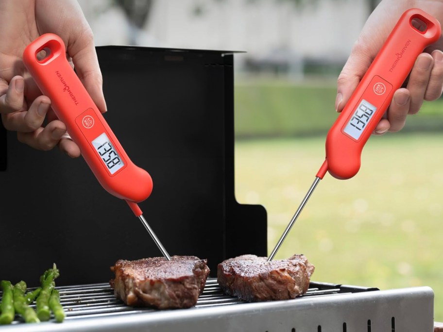people using red thermometers to check steak on grill 