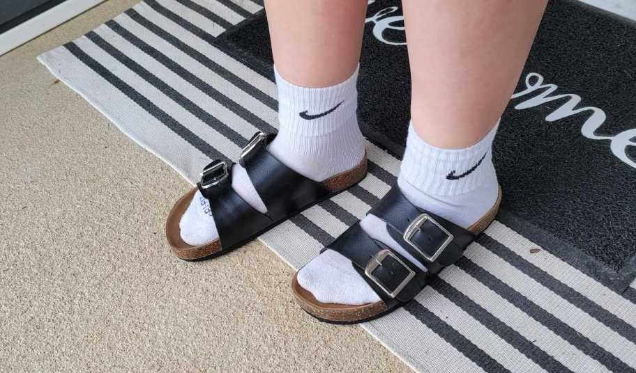 close up of feet with black buckle sandals and nike socks