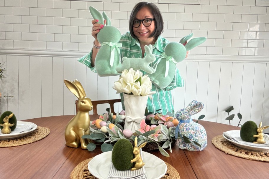 woman in green dress standing behind dinner table holding two flocked bunnies