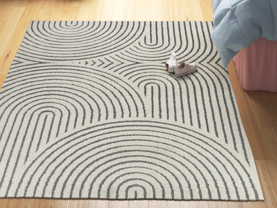 area rug with curved and straight lines on the floor next to a bed