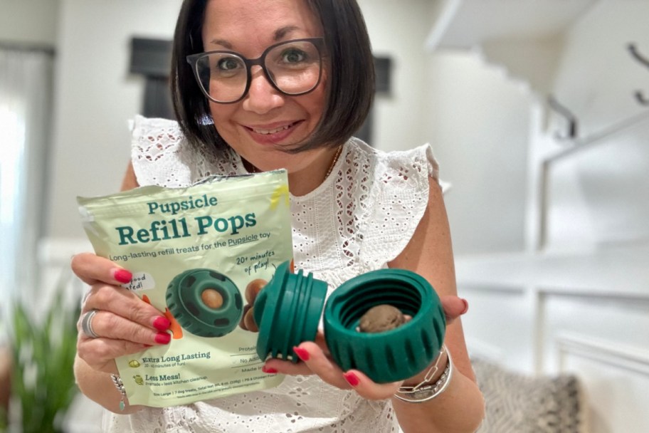 woman holding bag of dog treats and green dog toy