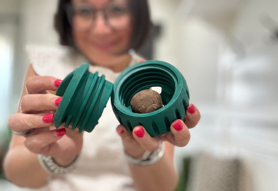 smiling woman holding an open dog toy with a treat inside it