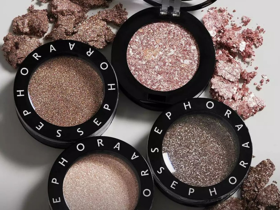 4 eyeshadow containers with loose eyeshadow around them