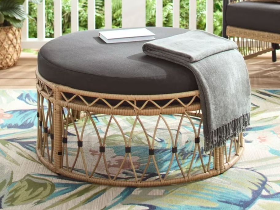 An outdoor round wicker ottoman on a patio