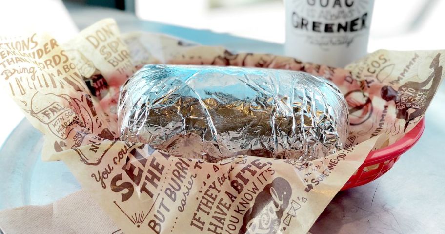 A Chipotle Burrito wrapped in foil in a basket