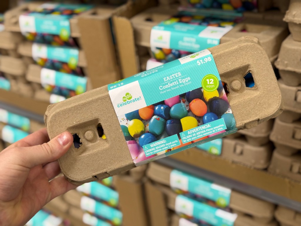 Person holding up cardboard box of Easter confetti eggs, inside Walmart store