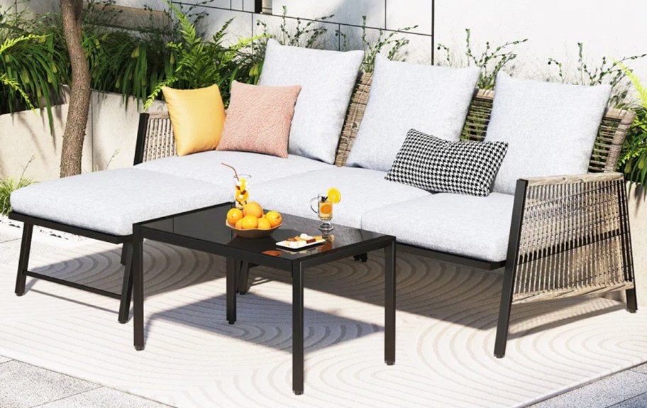 wicker patio sectional with white cushions and black coffee table