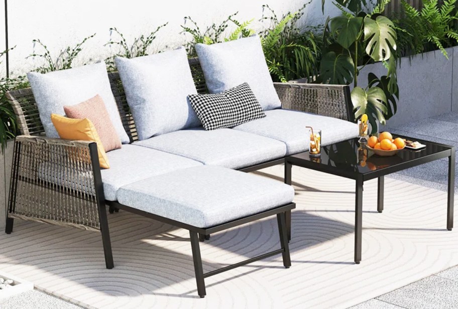 wicker patio sectional with white cushions and black coffee table