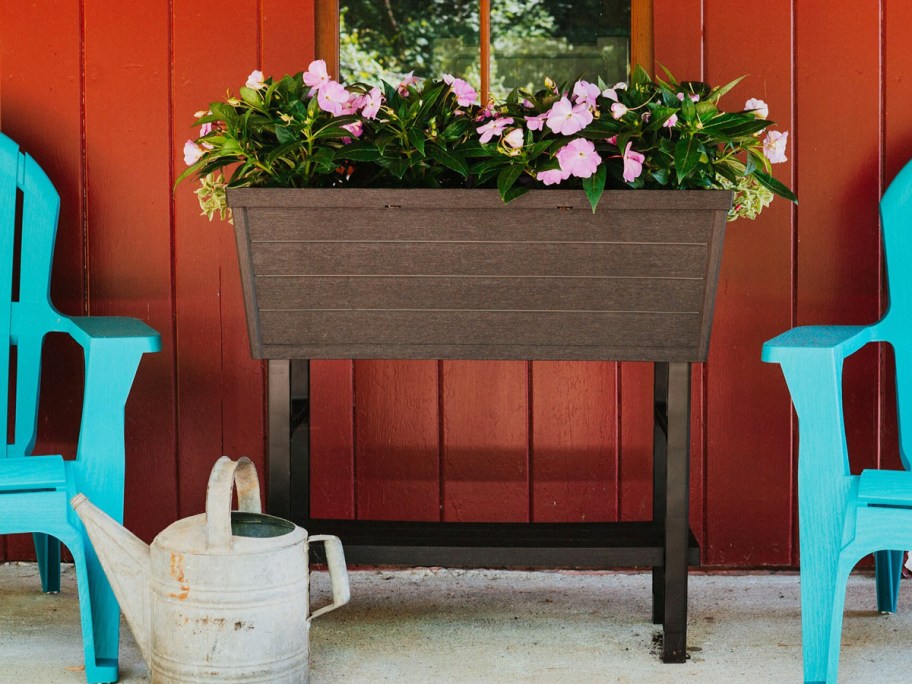 brown plastic raised gardne bed with pink flowers inside