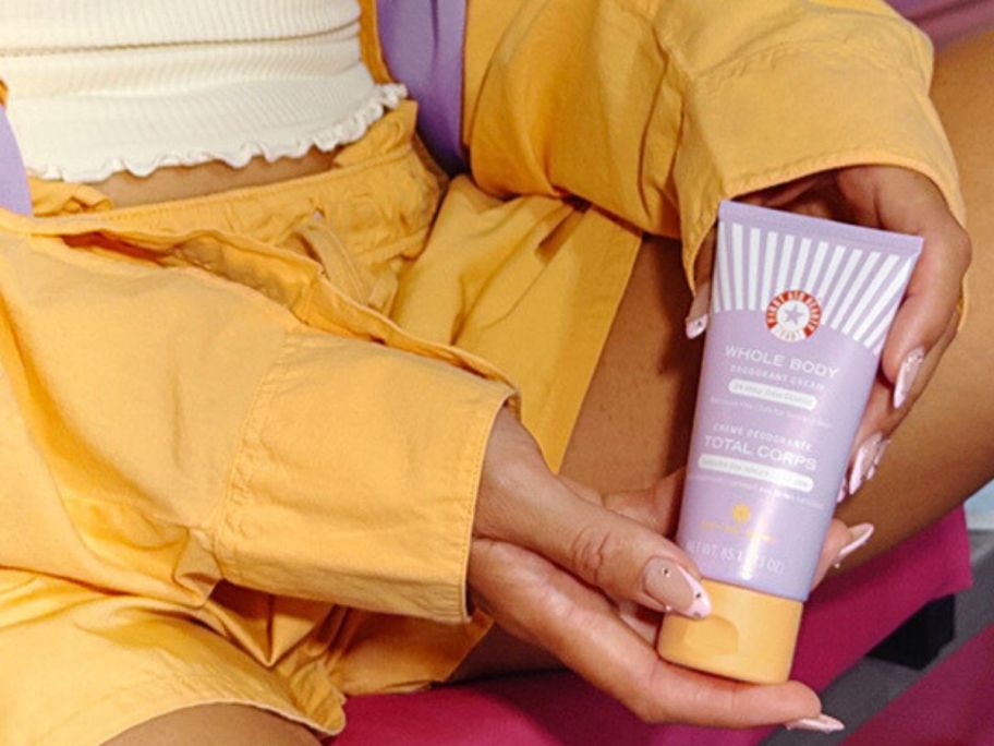 Woman holding a tube of First Aid Beauty Whole Body Deodorant Creamnext to her inner thigh