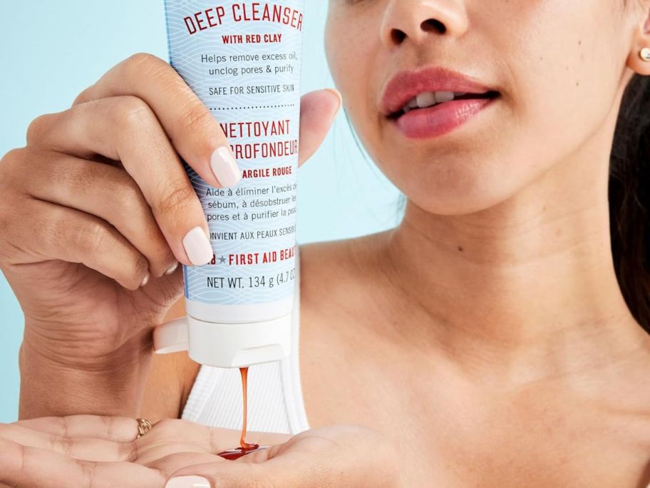 Woman squeezing First Aid Beauty Pure Skin Deep Cleanser w/ Red Clay into her hand