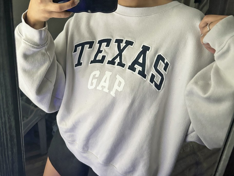 woman taking photo in mirror wearing texas gap sweatshirt
