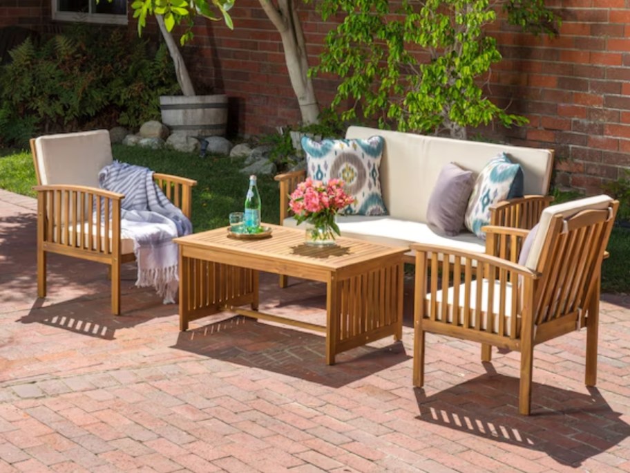 a wood patio set with sofa, chairs and coffee table on a back patio