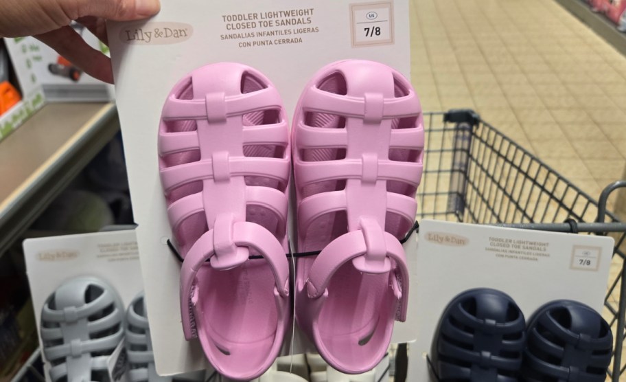 hand holding sandals in pink with other sandals in the cart