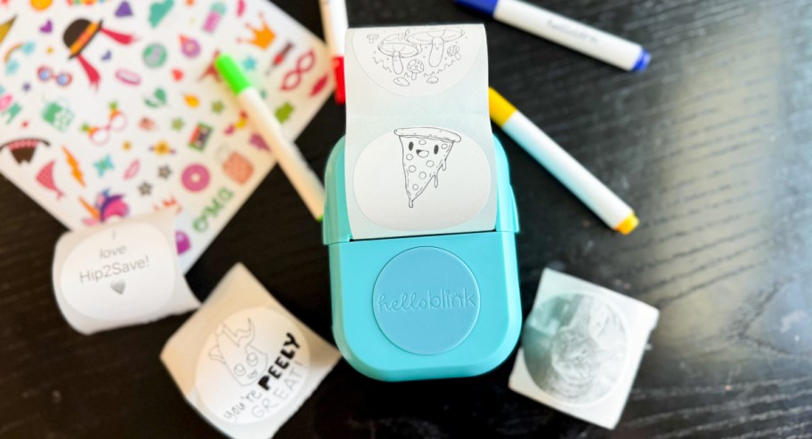 Hello Blink Sticker Maker displayed on a table with markers and other stickers 