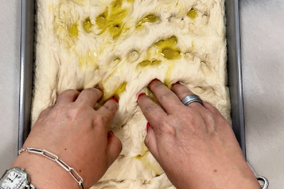 using fingers to smash dough for focaccia bread 