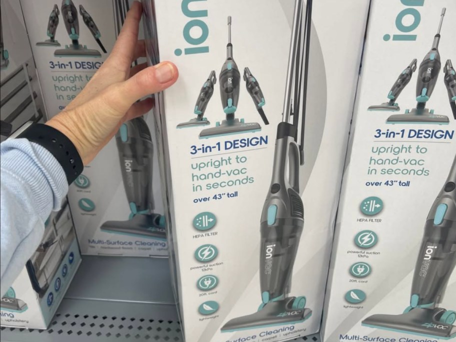 Woman grabbing ion VAC vacuum from store shelf inside Walmart