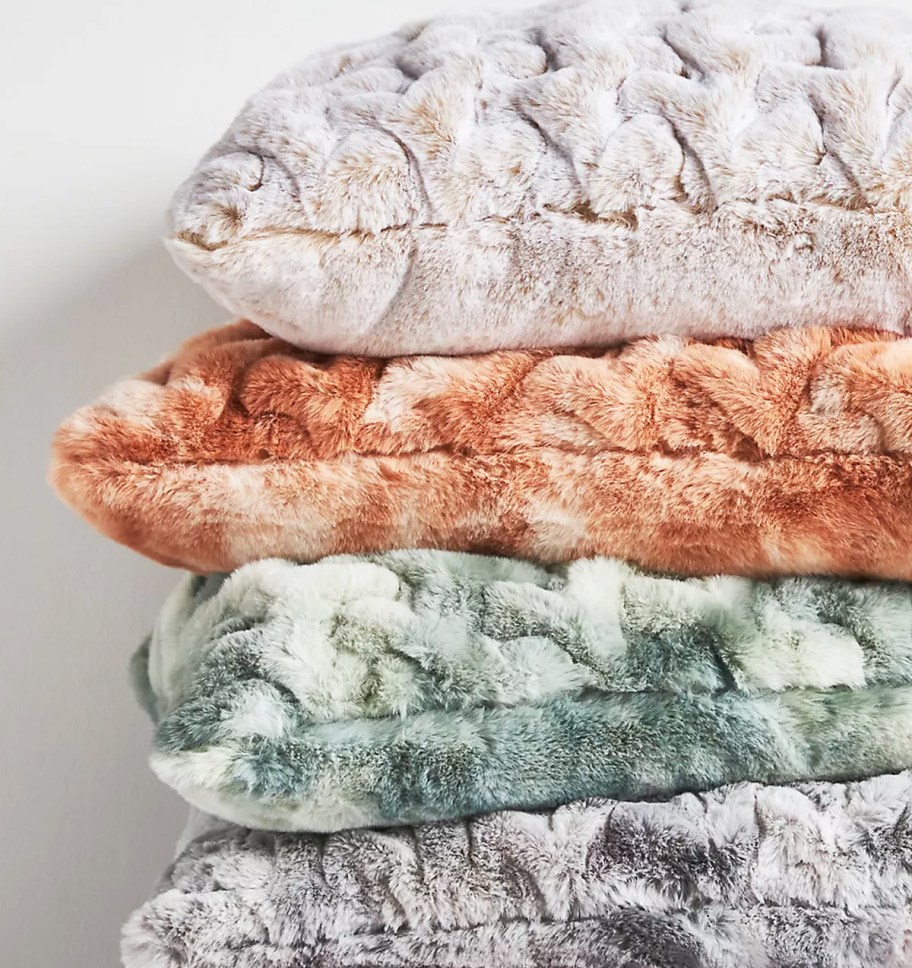 stack of fuzzy throw pillows in various colors