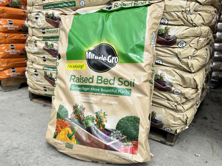 bag of Miracle-Gro Organic Raised Bed Soil leaning against pallet of more bags in garden center