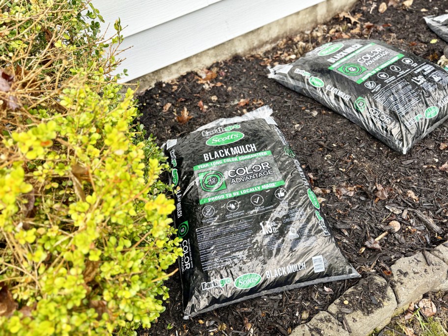 black bags of mulch in garden bed