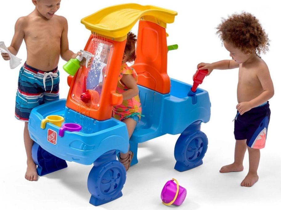 three little kids playing with a car shaped water table
