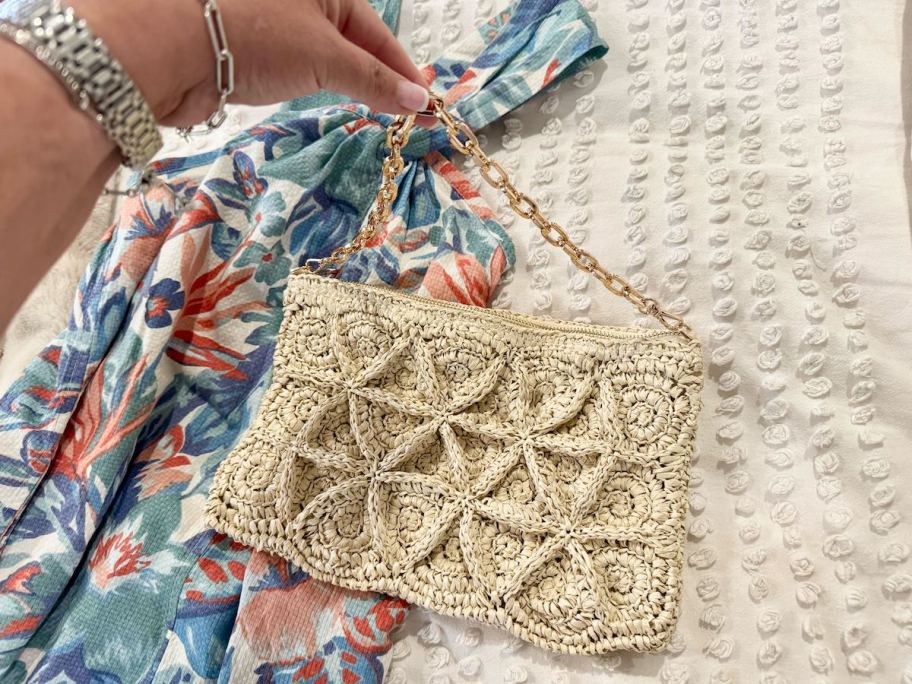 hand holding gold chain on straw purse